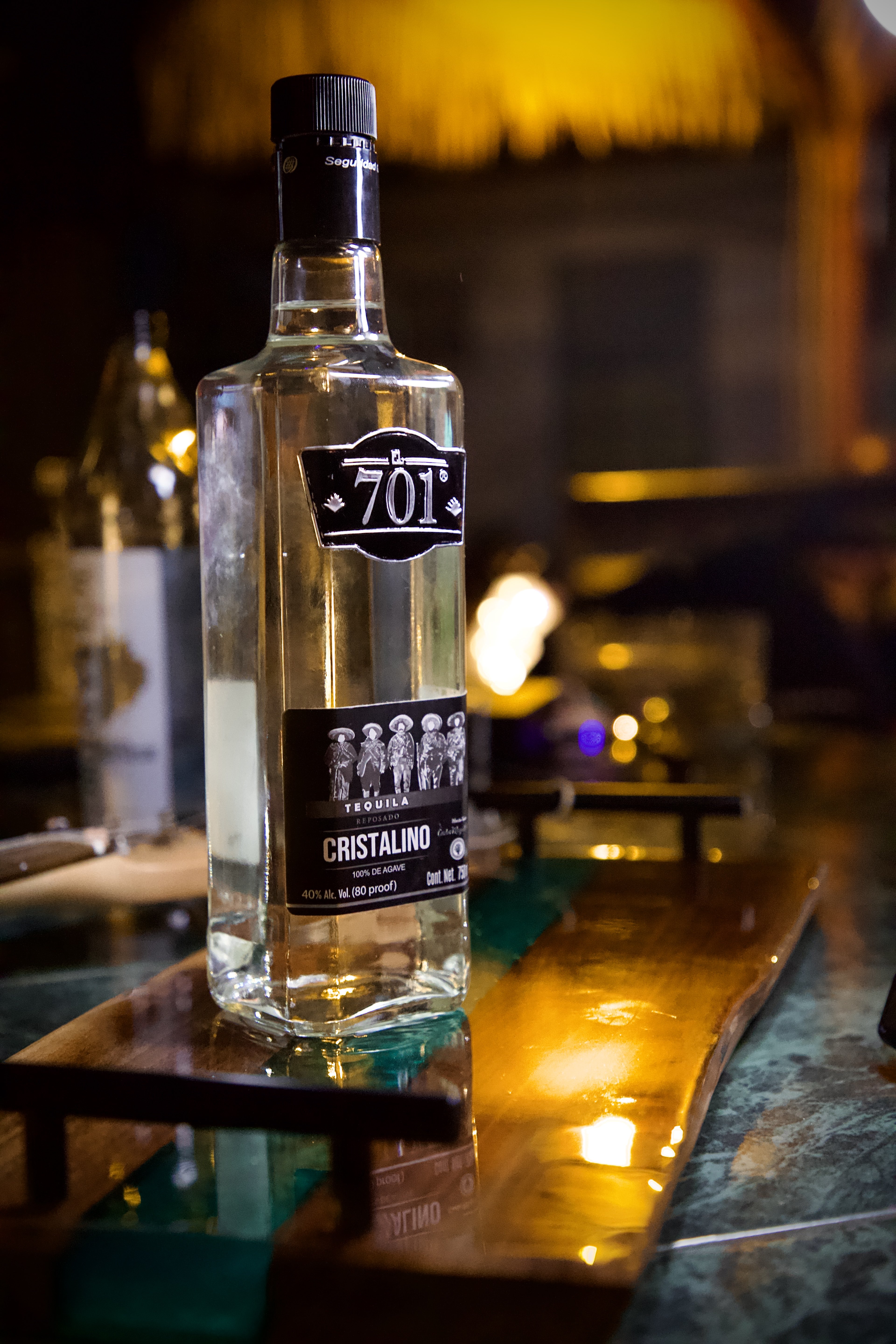 701 Cristalino tequila bottle glowing on a candlelit bar top