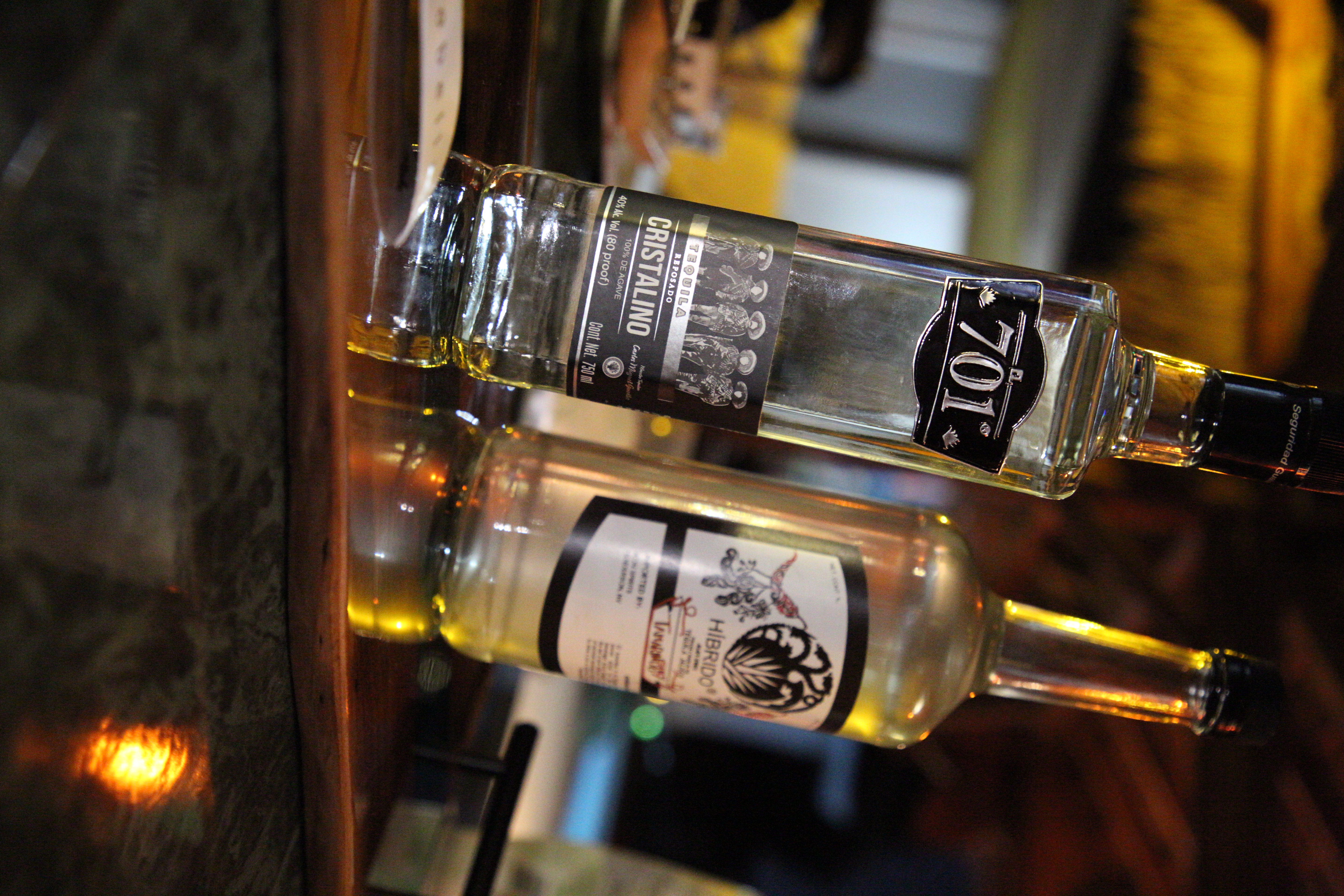 701 Cristalino tequila styled on a wooden serving tray in a warm, dim bar
